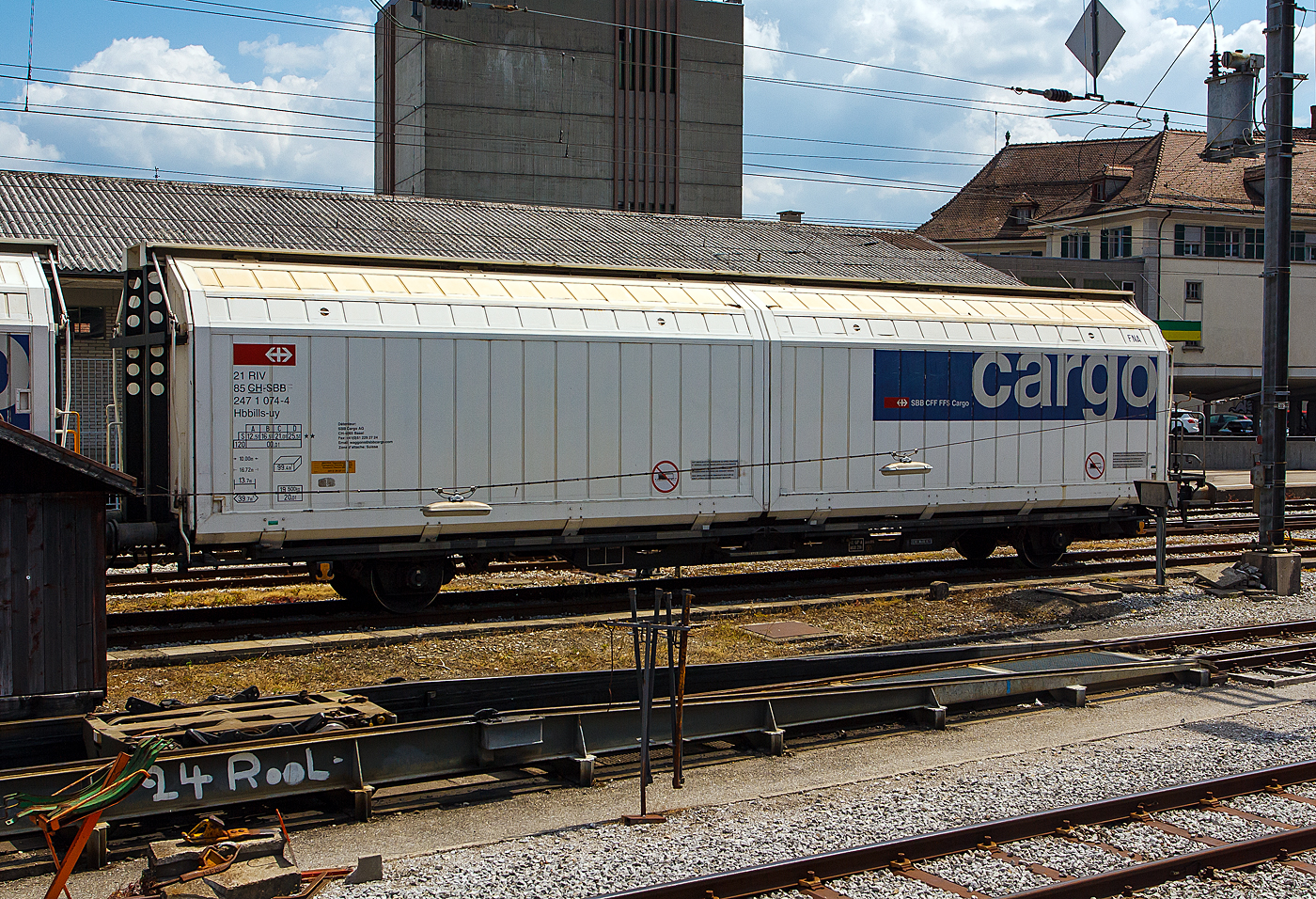 Zweiachsiger, gro�r�umiger Schiebewandwagen 21 85 2471 074-4 CH-SBB, der Gattung Hbbillns-uy, der SBB Cargo AG, abgestellt am 28.05.2012 beim Bahnhof Bulle. Davor die Rollbock-Anlage und ein Rollbock der tpf - Transports publics Fribourgeois (ex GMF - Chemins de fer fribourgeois Gruy�re–Fribourg–Morat). Das Bild entstand aus einem Zug heraus.

Der G�terwagen ist ein gedeckter temperaturgest�tzter zweiachsiger Schiebewandwagen mit fest verriegelbaren Trennw�nden. Er ist speziell geeignet f�r temperaturempfindliche G�ter im Bereich +/– 0� bis 20� Celsius. Wie zum Beispiel: Fleisch, Milchprodukte, Fr�chte/Gem�se, Pharmaprodukte, aber auch Schokoladenprodukte und 2012 gab es noch den G�terverkehr zur Cailler-Schokoladenfabrik nach Broc mittels Rollb�cken.

Die Be- und Entladung erfolgt seitlich, ca. die ½ Seite l�sst sich �ffnen. Das max. Ladegewicht betr�gt 25,5 t (38 Paletten)

TECHNISCHE DATEN:
Spurweite: 1.435 mm
L�nge �ber Puffer : 16.720 mm
Achsabstand:  10.000 mm
L�nge x Breite der Ladefl�che: 13.700 x 2.900 mm
Eigengewicht: 19.500 kg
Ladefl�che: 39,7 m�
Rauminhalt: 99,4 m�
Max. Ladegewicht: 21,0 t (ab Streckenklasse C) / 25,5 t (ab Streckenklasse D)
H�chstgeschwindigkeit: 100 km/h (beladen) / 120 km/h (leer)
Bremse: KE-GP-A (K)
Bremssohle: Jurid 816M
Feststellbremse: Nein
Kleinster, befahrbarer Gleisradius: R 35 m
Intern. Verwendungsf�higkeit: RIV

Besonderheit: Energieversorgung (Dieselaggregat oder externer
Netzbetrieb 400 V) Heiz-/K�hlaggregat (Thermoking SL 100e)
Isolierwert (0.55 W/m2 K), Temperaturbereich von O�C bis + 20�C
Fassungsverm�gen vom Kraftstofftank (Diesel) betr�gt 400 l.

Die Bedeutung der Gattungs- und Kennbuchstaben (hier Hbbillns-uy):
H Gedeckter Wagen in Sonderbauart
bb Ladel�nge 14 m und mehr
i Schiebew�nde
ll Verriegelbare/bewegliche Trennw�nde
s H�chstgeschwindigkeit 100 km/h
u Heiz/K�hlaggregat
y W�rmeisolation