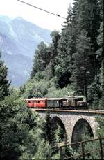 RhB Ge 6/6 I Nr.413 mit Personenzug mit Güterbeförderung auf dem Schmittentobel im August 1989.